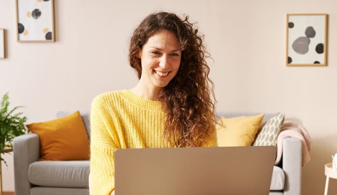 Senhora sorrindo usando laptop iniciando o Norton Safe Search.