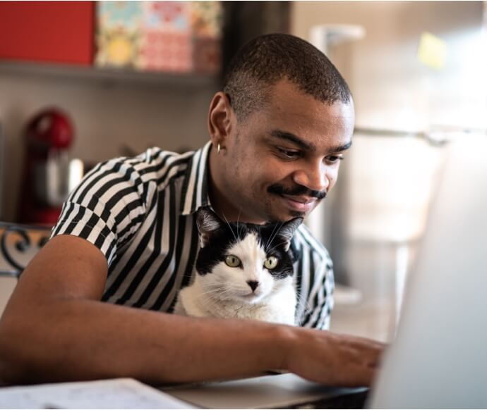 Homem usando notebook enquanto segura um gato