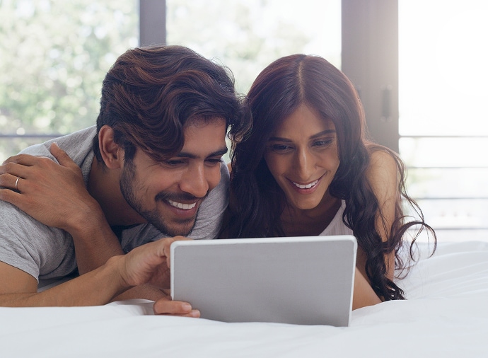 Homem e mulher rindo enquanto olham para um tablet.